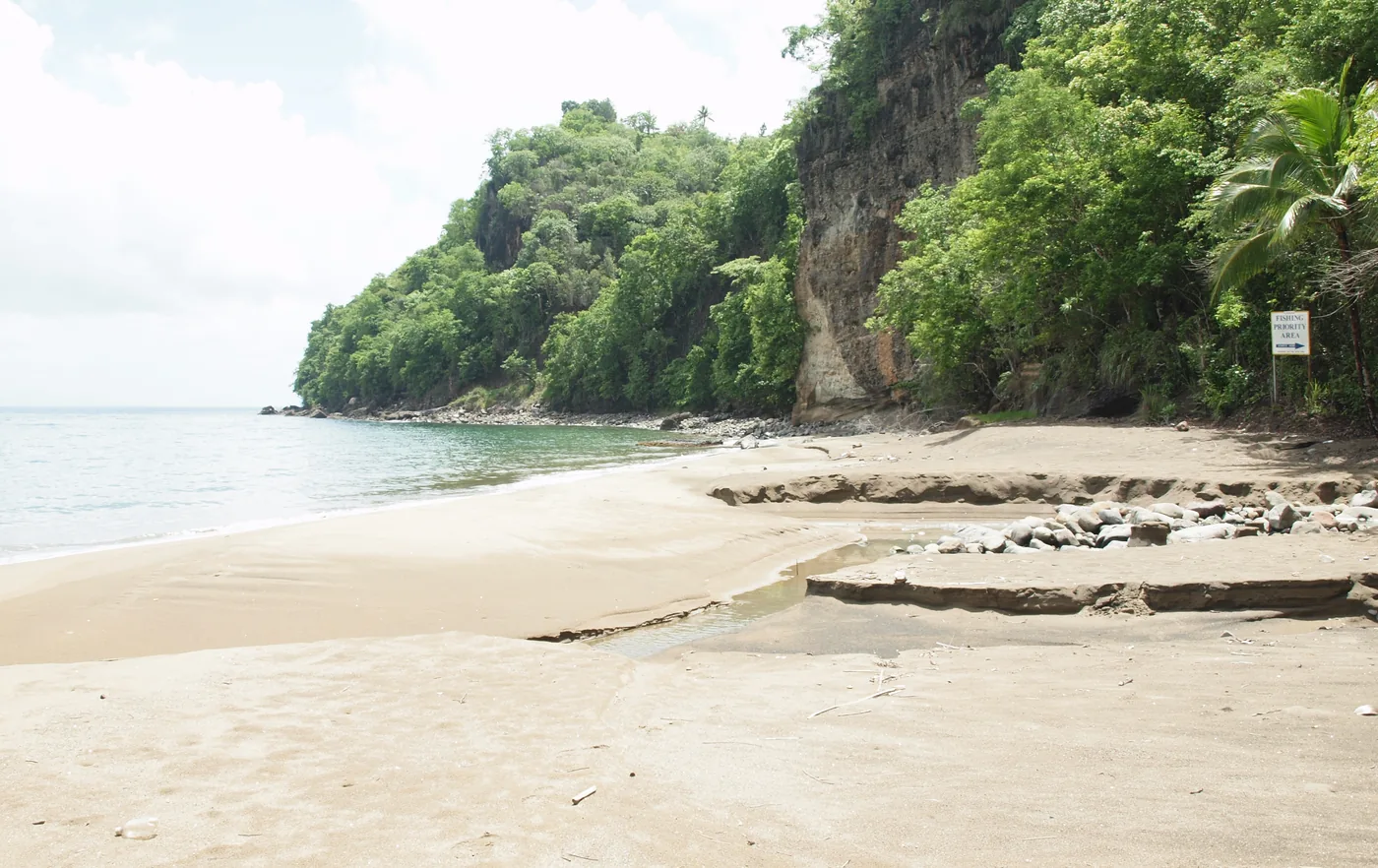 A quiet sandy beach under green cliffs at Anse Pilori, Saint Lucia